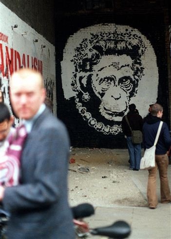 Járókelők nézik az angol Banksy, London legnevesebb falfestőjének alkotását a London Bridge közelében Londonban, 2002. május 31-én. A művész II. Erzsébet brit királynő aranyjubileuma, azaz trónra lépésének 50. évfordulója alkalmából készítette művét. - Fotó: MTI/EPA/Ben Fathers